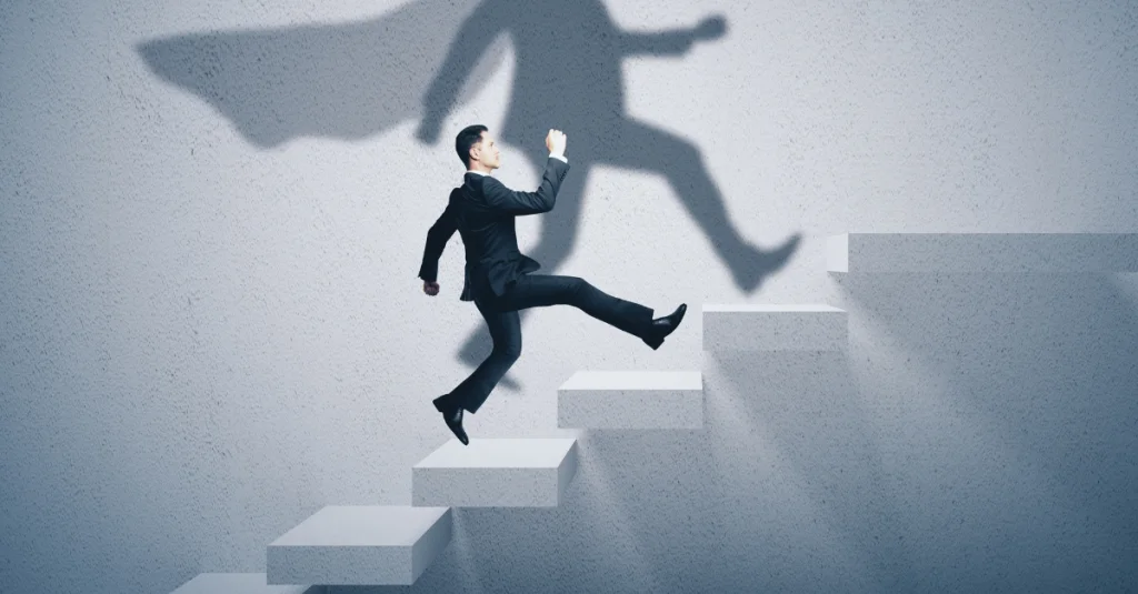 Man climbing stairs with superhero shadow representing how to overcome rejection and rebuild confidence during job search process