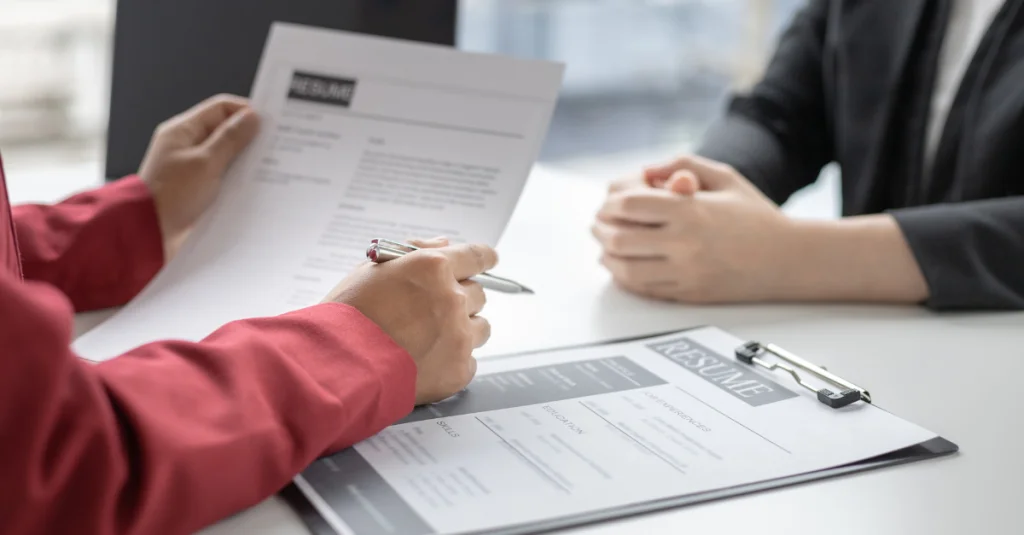 How to prepare for a job interview, hiring manager reviewing a candidate’s resume and preparing answers, illustrating the importance of preparation and documentation.